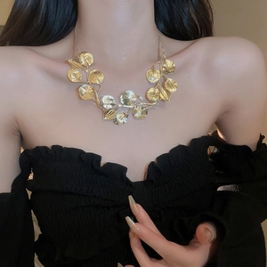 Close-up of a golden leaf pendant necklace on a model showcasing the minimalist floral design