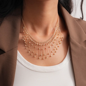 Detail of layered gold tassel necklace with metallic beads on model in autumn style