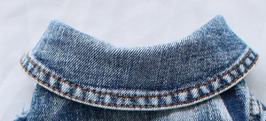 Macro shot of denim pet vest collar with orange double stitching and indigo texture