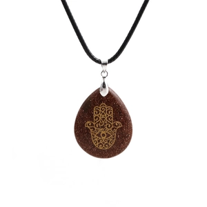 Macro shot of goldstone teardrop pendant with engraved Hamsa Hand and black cord