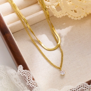Close-up of double-layered gold snake chain necklace with a zircon pendant in a wood box