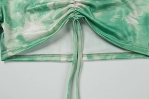 Detail of green tie-dye fabric featuring adjustable drawstring and ruched edge texture