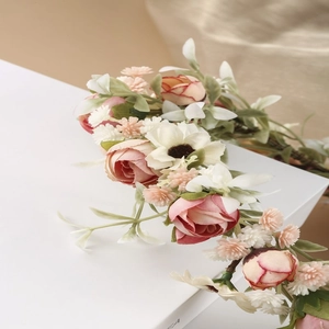 Dettaglio ravvicinato della corona di fiori boho con rose rosa e piccoli fiori bianchi