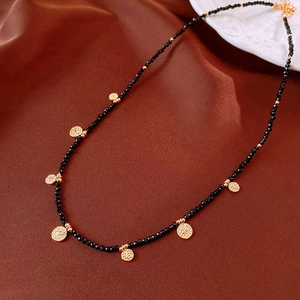 Detail of vintage black beaded necklace with golden coin pendants on silk background