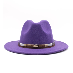 Detail of deep purple wool fedora featuring a bohemian woven band and golden shell ornament