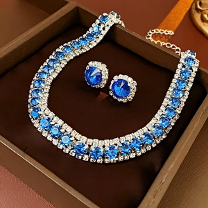 Detailed macro of silver luxury necklace and earrings with square blue rhinestones