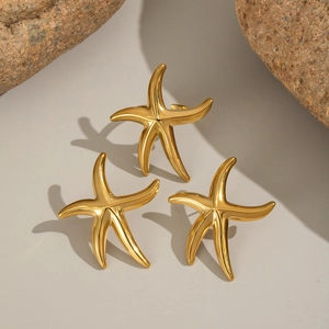 Detailed view of 18K gold plated starfish rings on natural stone props for beach style