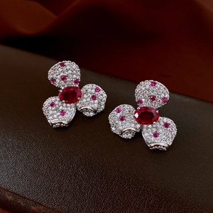 Detailed macro view of silver flower earrings with red gemstone and pink crystals
