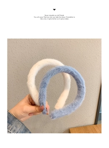 Close-up of white and blue plush headbands being held against a beige background