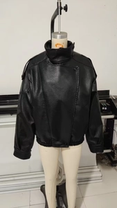 Detailed macro view of black faux leather jacket with litchi texture and standing collar