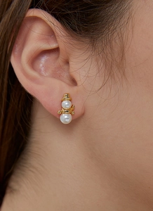 Macro close-up of a model wearing the gold-plated snowman earrings with pearl details