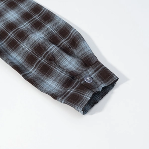 Close-up of long sleeve cuff with button on brown and blue plaid pattern shirt