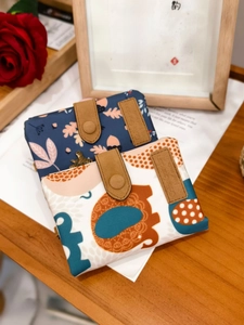 Detail of vintage canvas tri-fold wallets with floral prints and leather snap closure