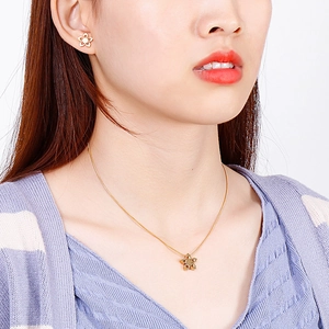 Detail of golden stainless steel flower necklace and earrings set worn by a model