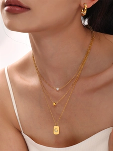 Close-up of triple-layer gold star and shell pearl necklace with moon pendant and C-hoop earrings