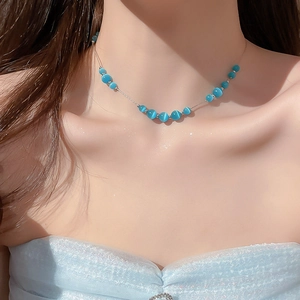 Close-up of light blue cat's eye stone necklace with silver chain on model collarbone