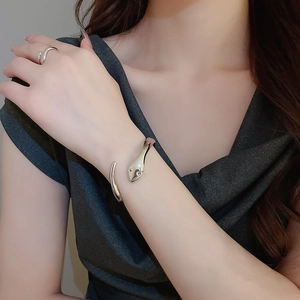 Polished silver snake-shaped open bracelet and ring set worn on model's hand