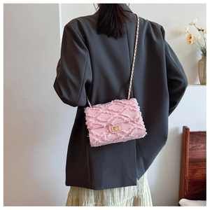 Detailed macro view of pink tweed chain bag with gold metal clasp and fringe texture