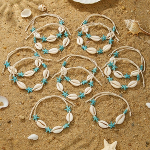 Macro shot of handmade shell bracelets and turquoise starfish beads on beach sand
