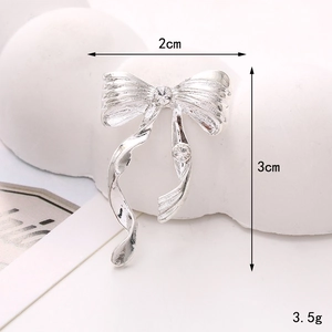 Macro shot of silver bow charm with white rhinestones, size 2x3cm and 3.5g weight