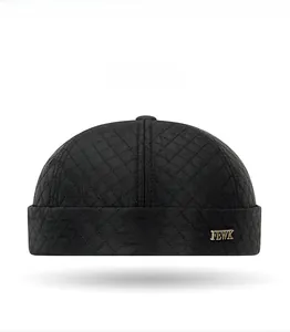 Detail view of black quilted skull cap with diamond stitching and FEWK metal logo