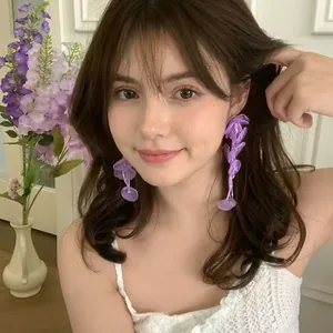 Detail of layered purple chiffon flower petal earrings worn by a model in soft lighting