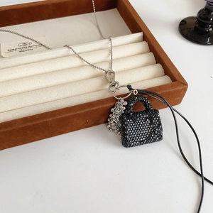 Gros plan sur le pendentif sac à main noir orné de cristaux et chaîne argentée