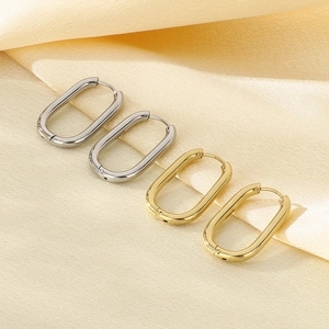Minimalist oval stainless steel hoop earrings in gold and silver on silk background