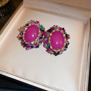 Detail of vintage oval earrings with purple stones and colorful beaded borders