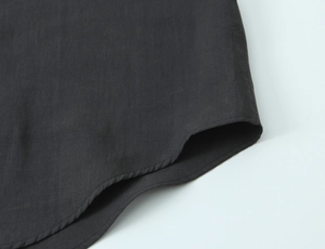 Detailed view of curved hemline and fine stitching on black poplin cotton fabric