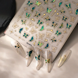 Macro shot of 3D emerald butterfly nail stickers with gold embossed edges and stars