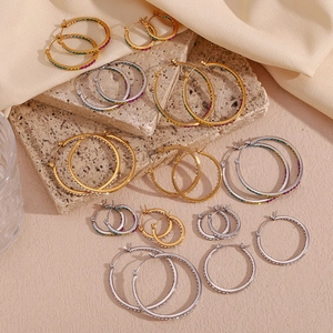 Detail of gold and silver hoop earrings with colored crystals on stone and silk fabric