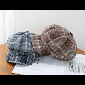 Classic plaid newsboy caps in grey and brown wool blend texture on a wooden desk