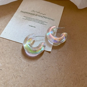 Iridescent acrylic C-shaped hoop earrings displayed on a rustic brown paper background