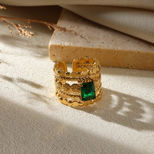 Detail of gold multi-layer wide ring with emerald gemstone and floral textures