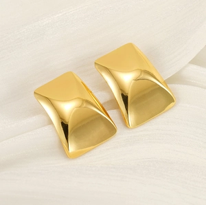 Macro detail of 18k gold plated rectangular earrings with mirror polish on white silk