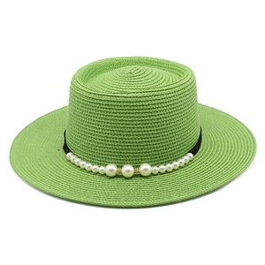 Dettaglio di un cappello di paglia verde con nastro nero ed eleganti perle bianche applicate