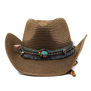 Detail of straw cowboy hat with turquoise stone, ethnic bands and pink tassels