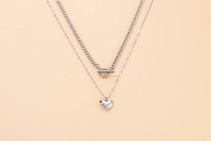 Detail of silver double-layer titanium steel necklace with heart pendant and OT clasp