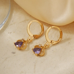 Detailed view of heart-shaped purple stone earrings with gold metal and diamond accents