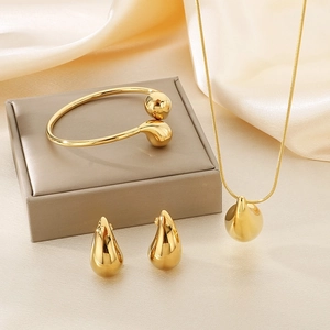 Golden chunky teardrop jewelry set with necklace, earrings and open cuff on silk fabric