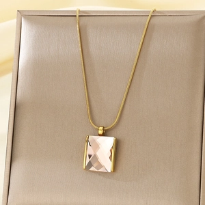 Detail of light pink rectangular gemstone pendant on golden snake chain over silk box