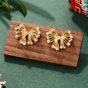 Detail shot of golden bow earrings with sparkling white cubic zirconia on a wooden display
