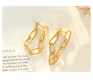 Detailed view of golden paperclip chain earrings on a vintage book with soft lighting