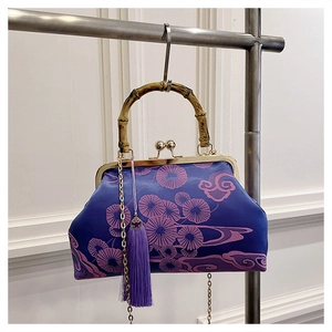 Detail einer blauen Satin-Sticktasche mit goldenem Verschluss und Bambusgriff