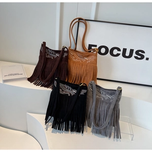 Detail showing embroidered patterns and decorative fringe on suede shoulder bags