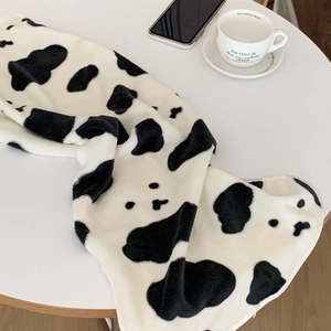 Detailed view of soft cow print coral fleece towel on a table with cozy home decor