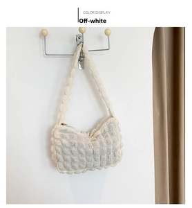 Detail of cream white bubble texture shoulder bag hanging on a minimalist wall