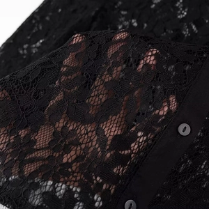 Close-up of black lace fabric texture with hollow patterns and single button detail