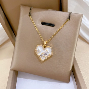 Detail of a gold titanium heart necklace with white mother of pearl and zircon stones